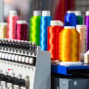 Spools of color threads closeup, spinning machine. Cloth factory, weaving, textile production, clothing industry, sewing fabric